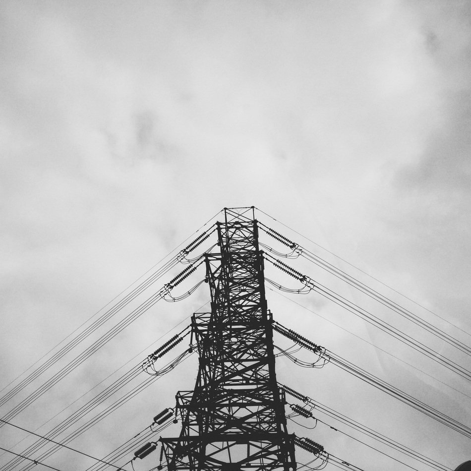 electric lines on a pillar under the sky with clouds