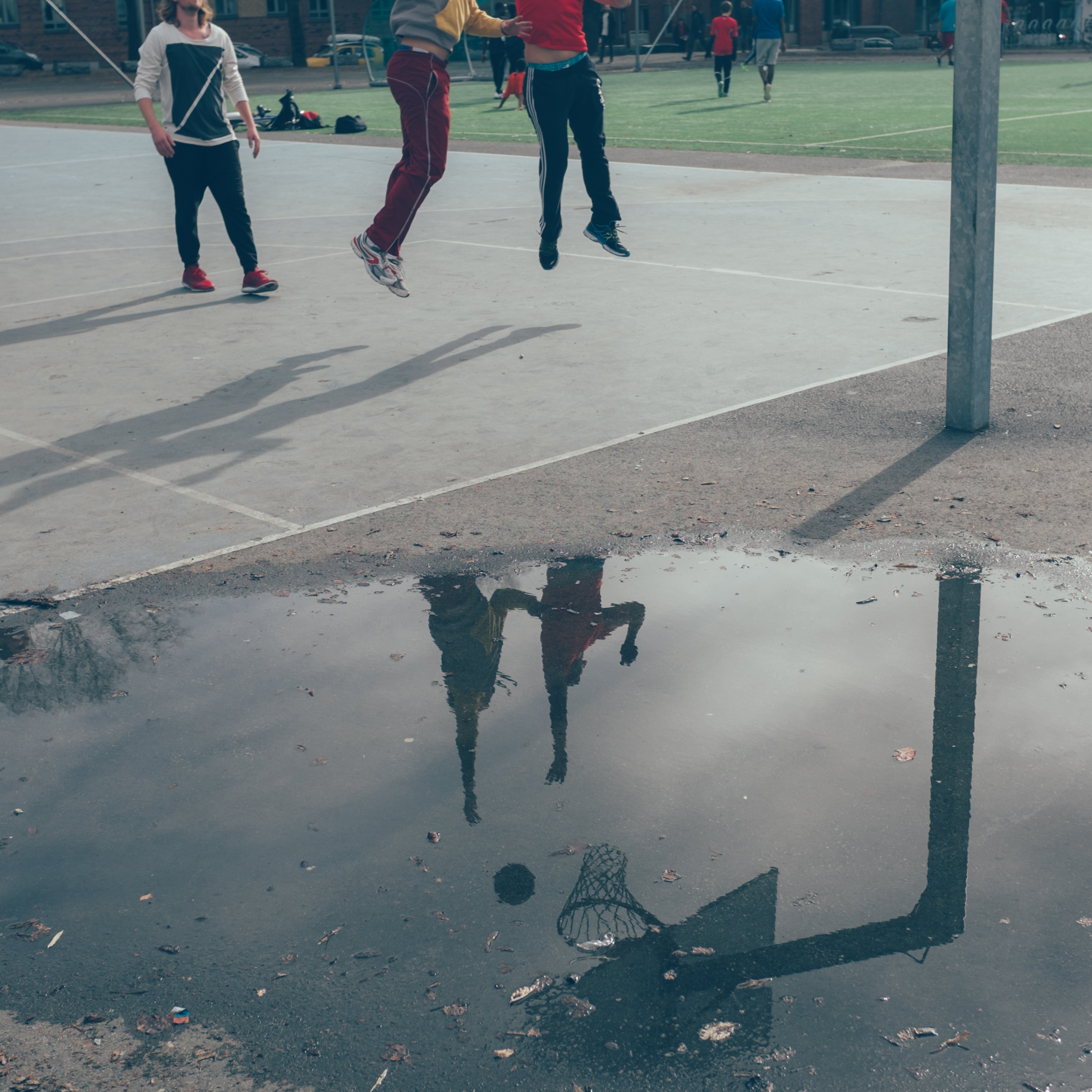 Reflection of kids playing basketball on puddle free image download