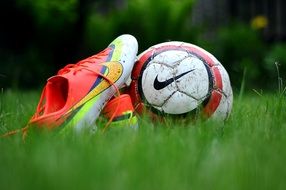 multicolored football boots and soccer ball on the grass