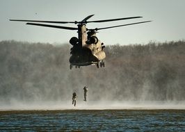 military helicopter with soldiers over the water