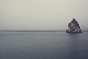 rock in the ocean among calm water