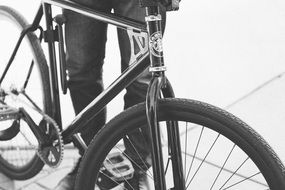 black and white photo of the legs of a teenager and a sports bike