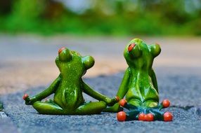 two ceramic frog figures hold hands and look up