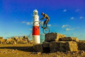 cyclist jumps from the rock near the lighthouse