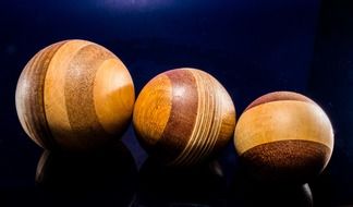 three handmade wooden balls in a dark