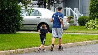 young man and child boy jogging at street, back view