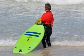 boy with green surfboard in water