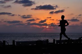 A man runs along the embankment at sunset