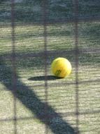 yellow tennis ball in shadow on the court