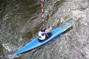 athlete in blue canoe floats on water
