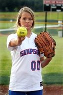 uniformed young girl with ball and glove on field, softball player