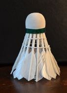 white badminton shuttlecock at dark surface