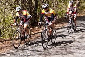 three uniformed young persons cycling on road