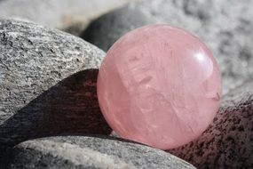 pink quartz ball on gray stones close up