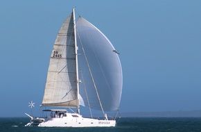Sailboat for water sports on water and blue sky background