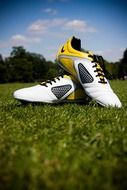 white and yellow football boots on the lawn