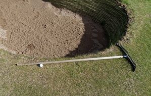 sand, rake and ball on a golf course