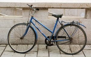 old blue women's bicycle at wall