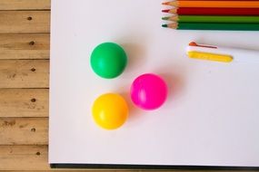 colored balls with pencils on a white sheet