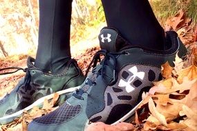 man in sneakers stands on dry leaves