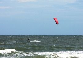 skydiver with a red parachute over the ocean