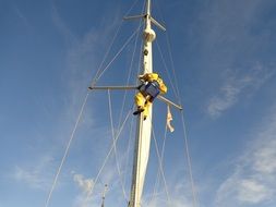 Human repairing mast on a sail boat