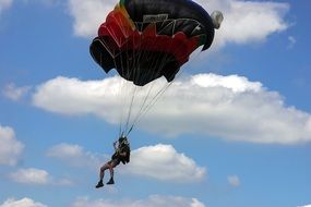 Jump with a parachute on a cloudy sky background