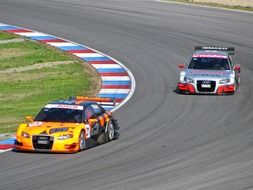 yellow car in front of the white car in the race