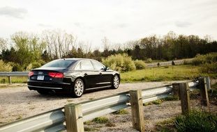 black car stands on the road near the fence