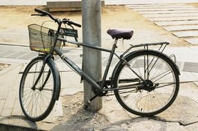 Bicycle with a basket near the pillar