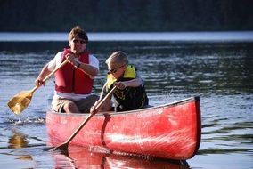son and father paddling in canoe on river