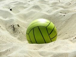 green volleyball ball in the sand on the beach of the Baltic Sea