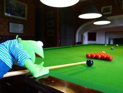 toy frog plays billiards with the balls