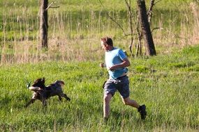man with a dog running on the meadow