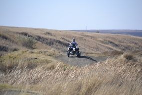 man rides quad in wilderness