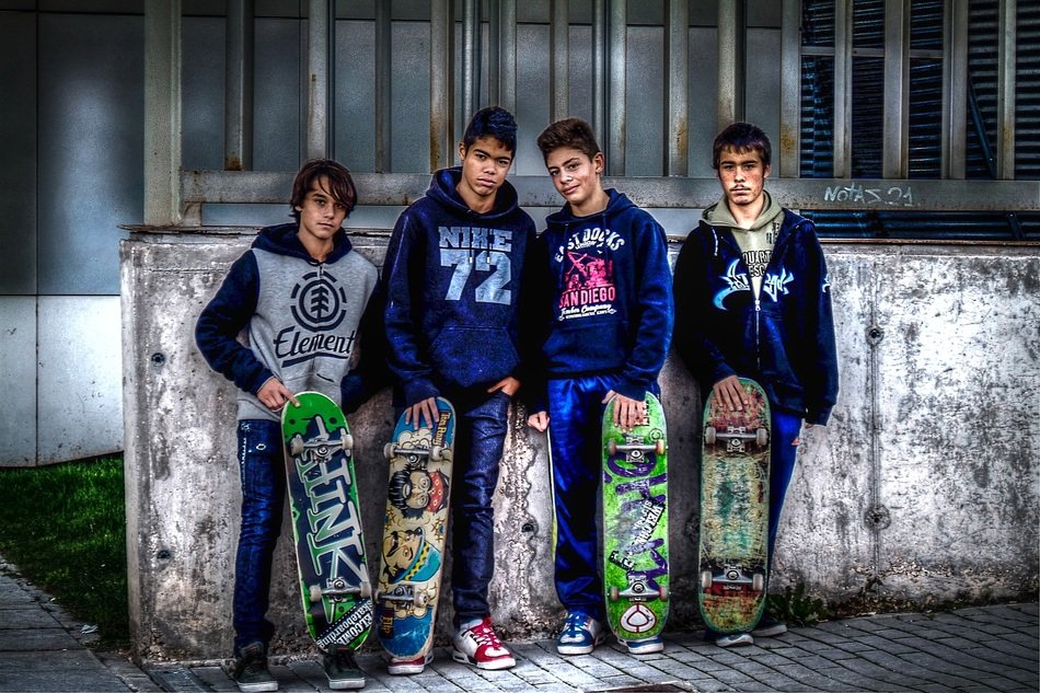 four boys with skate boards at wall
