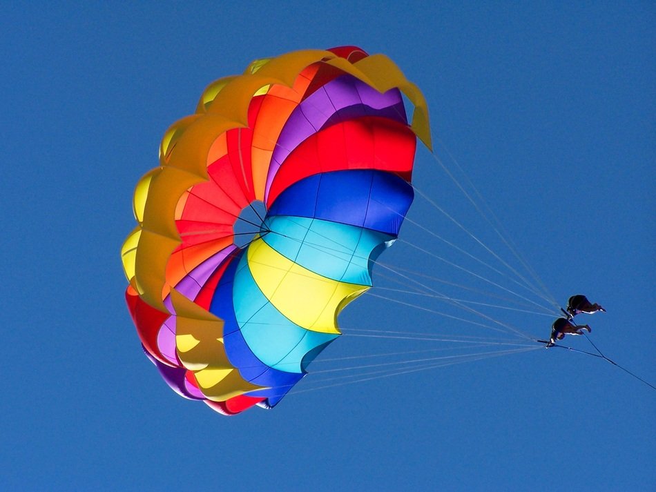 parasailing together on a multi-colored parachute