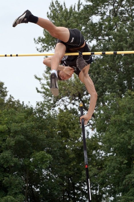 Athlete in a jump against the background of green trees