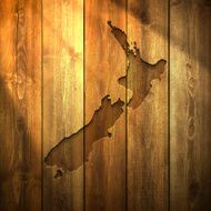New Zealand Map on lit Wooden Background