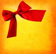 festive red bow on yellow textured background - copy space
