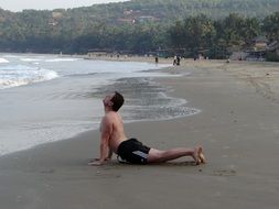 Man on the beach in yoga pose