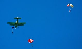 airplane and skydivers on blue sky background