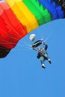 Bottom view of a parachutist with a colorful bright parachute on blue sky background