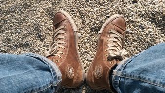 legs in brown sport shoes on pebbles