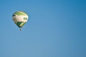 green and white balloon flying in blue sky