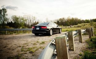 black car on the road near the wooden fence