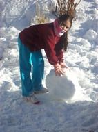 child rolls a snowball