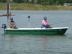 two fishermen in a green boat on the water