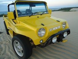 yellow sports car on sand beach