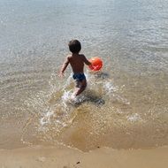 child with a ball in the water of the Ionian Sea in summer